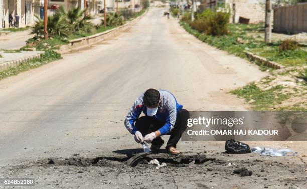 Syrian man collects samples from the site of a suspected toxic gas attack in Khan Sheikhun, in Syria's northwestern Idlib province, on April 5, 2017....