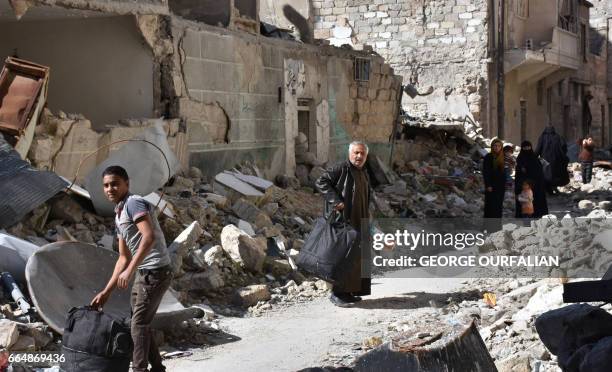 Syrians, who fled their hometown due to the fighting, carry their belongings upon their return to Aleppo's Myassar neighbourhood on April 5, 2017.
