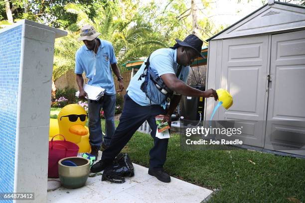 Barrington Sanders and Joseph Blackman with the Miami-Dade County mosquito control department inspect a neighborhood for any mosquitos or areas where...