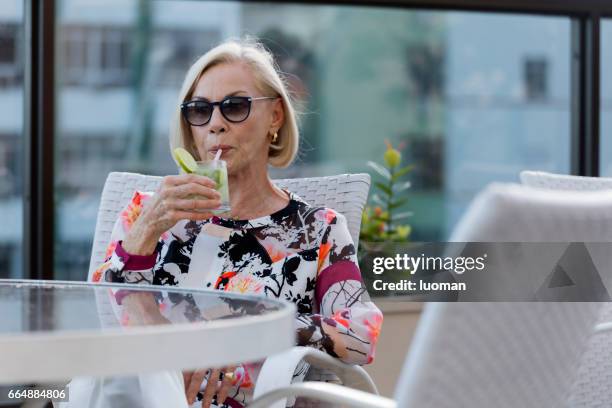 elegante dama de edad beber una caipirinha - contente fotografías e imágenes de stock