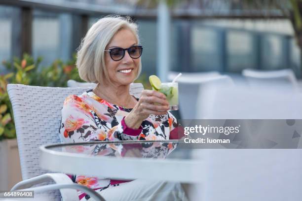 elegante oude dame drinken een caipirinha - foco seletivo stockfoto's en -beelden