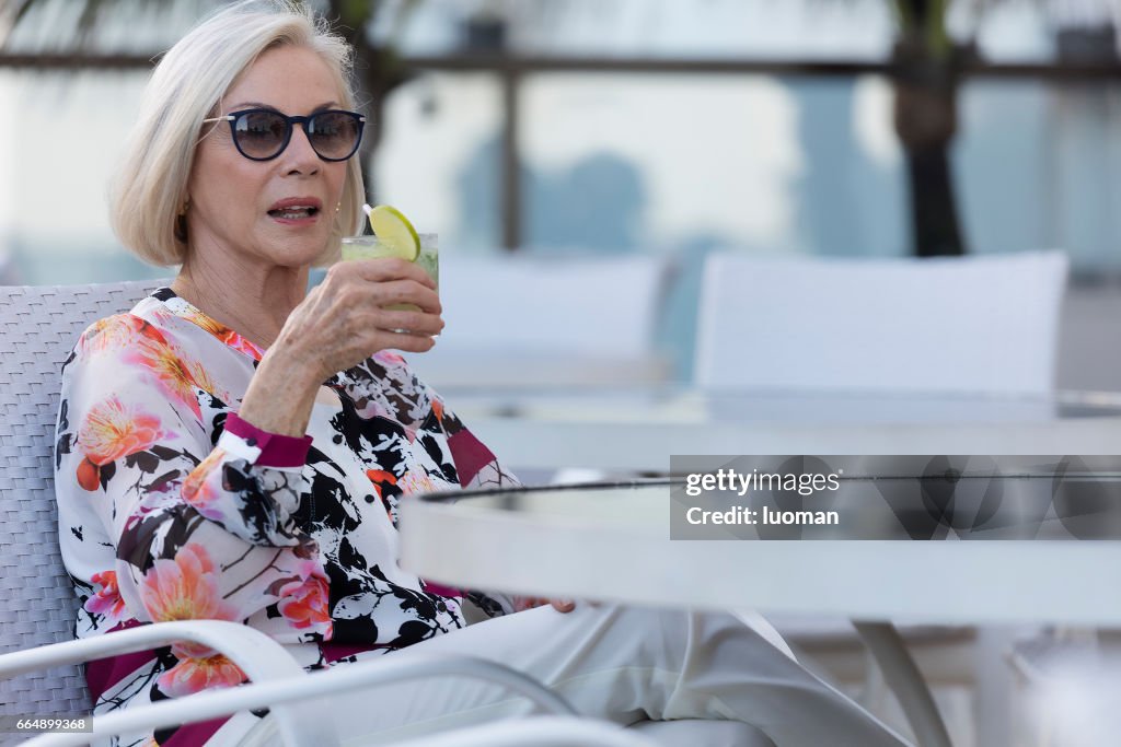 Elegant old lady drinking a caipirinha