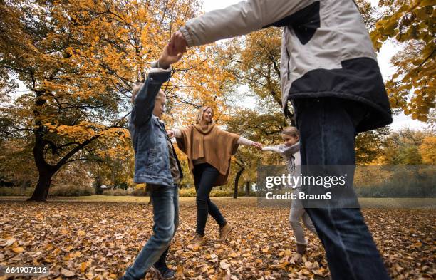 playful family playing ring-around-the-rosy in the park. - ring around the rosy stock pictures, royalty-free photos & images