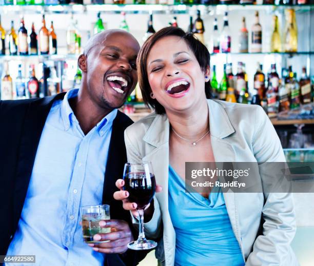 laughing couple celebrating at cocktail bar - chink eye stock pictures, royalty-free photos & images