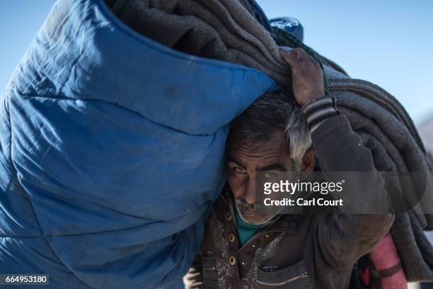 Man carries bedding on his shoulders in Hamam al-Alil refugee camp where large numbers of people have settled after being displaced by fighting...