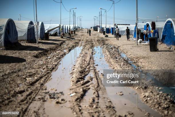 Tents sit either side of a muddy road in Hamam al-Alil refugee camp where large numbers of people have settled after being displaced by fighting...