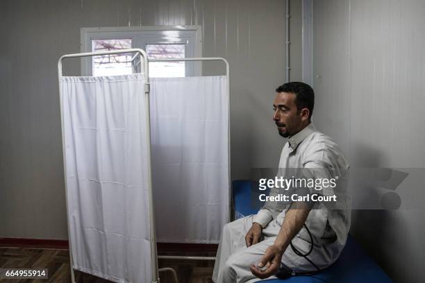 Man sits still as he is treated by a doctor in Hamam al-Alil refugee camp where large numbers of people have settled after being displaced by...
