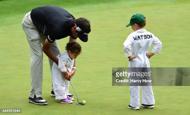 Bubba Watson of the United States helps his daughter Dakota putt as son Caleb looks on during the Par 3 Contest prior to the start of the 2017...