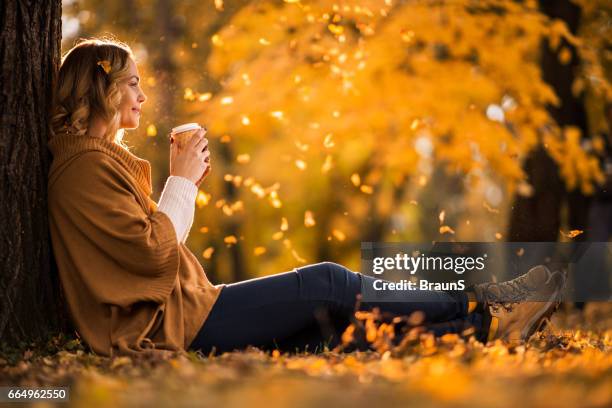 smiling woman enjoying in cup of coffee in autumn park. - autumn coffee stock pictures, royalty-free photos & images