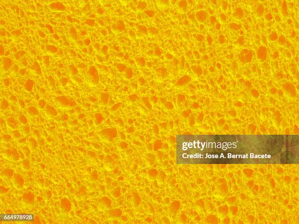 full frame of coarse and wavy textures of colored foam, yellow background - spugna per le pulizie foto e immagini stock