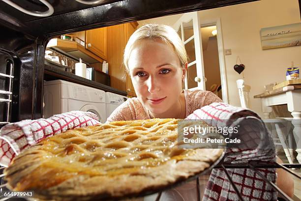woman taking apple pie out of oven - removing stock pictures, royalty-free photos & images
