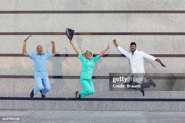 team of happy doctors celebrating success and jumping of joy. - doctor leaping stock pictures, royalty-free photos & images