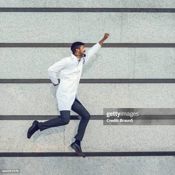 playful african american doctor flying against the wall. - doctor arms raised stock pictures, royalty-free photos & images