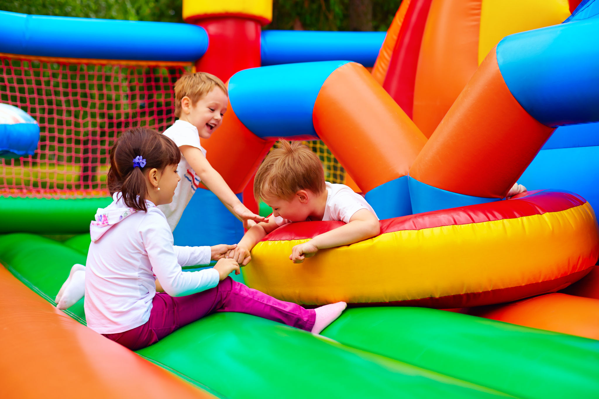 Kids jumping in colorful bounce houses at a Kansas City party