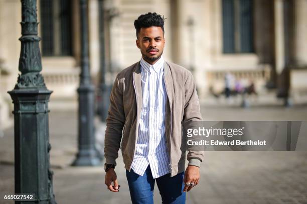 Theo Kimbaloula, fashion blogger, wears a Wac beige jacket, a Wac shirt, Asos blue jeans, and The Kooples beige suede boots, at the Louvre, on April...