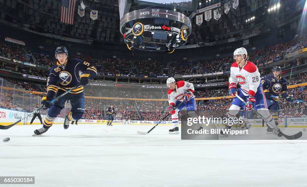 Rasmus Ristolainen of the Buffalo Sabres skates after the puck while being watched by Nathan Beaulieu and Brian Flynn of the Montreal Canadiens...