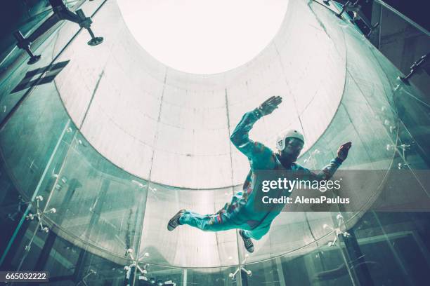 indoors skydiving - one young man practising freefall simulation - skydiving stock pictures, royalty-free photos & images