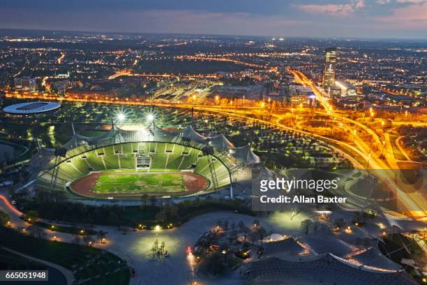 aerial view of munich's olympic stadium illuminated at night - munich stock-fotos und bilder