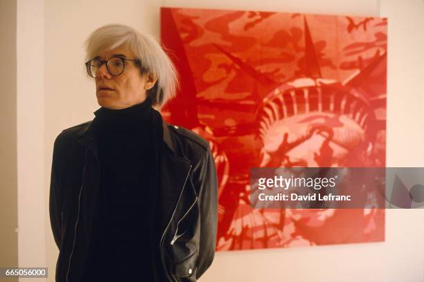 American Painter Andy Warhol, standing in front of a painting, circa 1970.