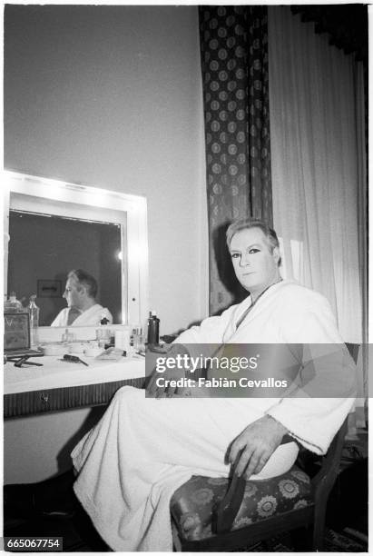 French actor Michel Serrault sits in front of a make-up table, in a peignoir with his face powdered, on the set of french director Edouard Molinaro's...