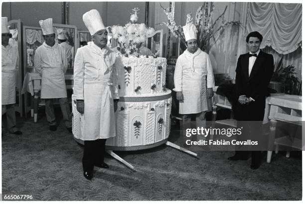 Italian actor Ugo Tognazzi dressed as a chef stands with other chefs in front a fake giant cake, on the set of French director Edouard Molinaro's...