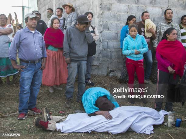 People stand before the body of a person killed during a clash between villagers and state police officers in Arantepacua, Nahuatzen municipality,...