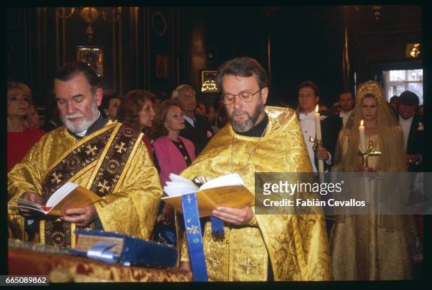 Priests hold religious books as Olga Rostropovich and Olaf Guerrand-Hermes stand in the background during their wedding at the orthodox church.