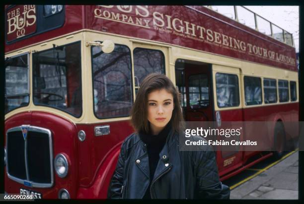 Jane March stands in front of a bright red double-decker sightseeing bus. The British actress plays the role of the young girl in French director...