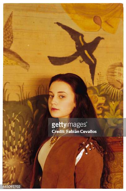 Young actress Monica Keena, wearing an aristocrat's dress, poses for a portrait with a tapestry on the wall behind her on the set of the movie Snow...