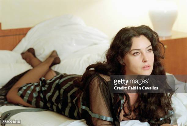 Italian actress Monica Bellucci, wearing a black dress, lies on a bed on the set of the Italian director Giuseppe Tornatore's film Malena. On the day...