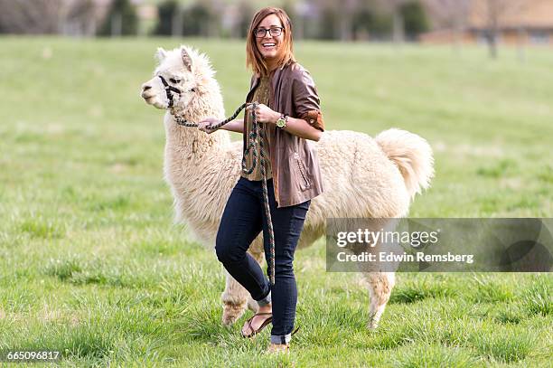 young woman walking with an alpaca on a lead - alpaca stock pictures, royalty-free photos & images