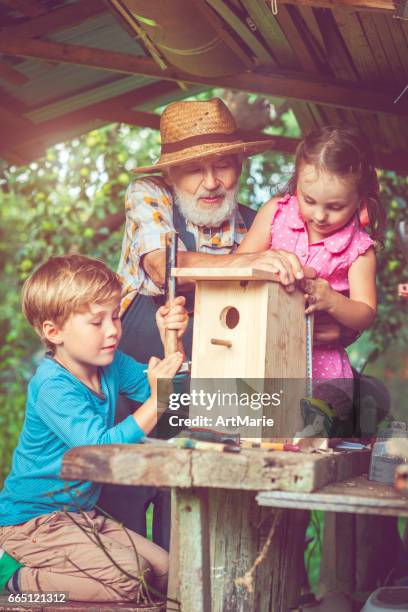 opa mit kinder machen vogelhaus - vogelhäuschen stock-fotos und bilder