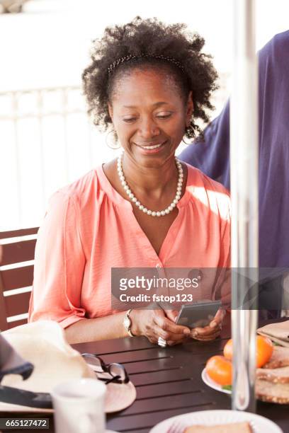 senior volwassen vrienden met behulp van technologie op café. - african american restaurant texting stockfoto's en -beelden