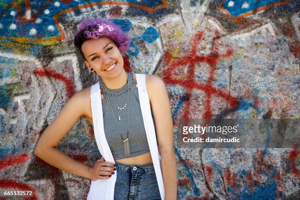 niña joven inconformista sonriente posando contra la pared de graffiti - dyed red hair fotografías e imágenes de stock