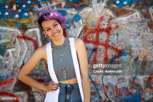 smiling young hipster girl posing against graffiti wall - punk girl stock pictures, royalty-free photos & images