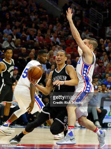 Jeremy Lin of the Brooklyn Nets drives to the basket as T.J. McConnell of the Philadelphia 76ers defends in the first half during an NBA game at...