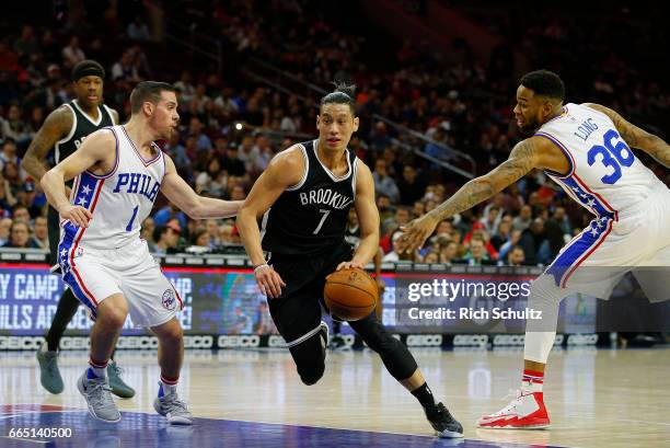 Jeremy Lin of the Brooklyn Nets drives to the basket as T.J. McConnell and Shawn Long of the Philadelphia 76ers defend in the first half during an...