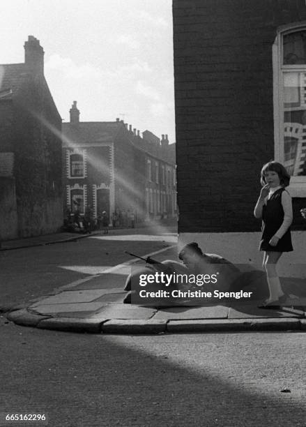 Little girl stands in a ray of sunshine next to a soldier on a Derry/Londonderry street on Bloody Sunday. English soldiers shot and killed thirteen...