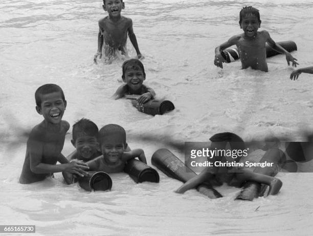 As the Vietnam War draws to a close, Cambodian children play in the Mekong river with empty shell cartridges.