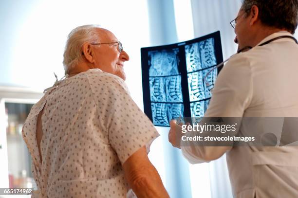 l'uomo anziano discute a raggi x con il dottore. - colonna vertebrale foto e immagini stock