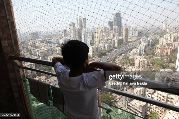 Young boy looks across the skyline on March 8, 2017 in Mumbai, India. Mumbai, also called the 'Maximum City', is the financial hub of India and is...