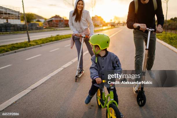 active family on wheels - father helping son wearing helmet stock pictures, royalty-free photos & images