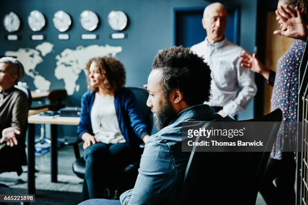 businessman listening during team meeting in office - clock person desk stockfoto's en -beelden