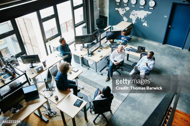 coworkers having informal project meeting in high tech office overhead view - clock person desk stockfoto's en -beelden