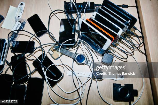 smartphones and smartwatches charging on desk in high tech office - abundance stock pictures, royalty-free photos & images