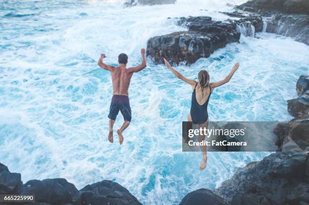 hermosa pareja salto de acantilado en el océano - salto desde acantilado fotografías e imágenes de stock