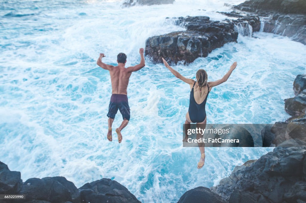 崖から海に飛び込む美しいカップル