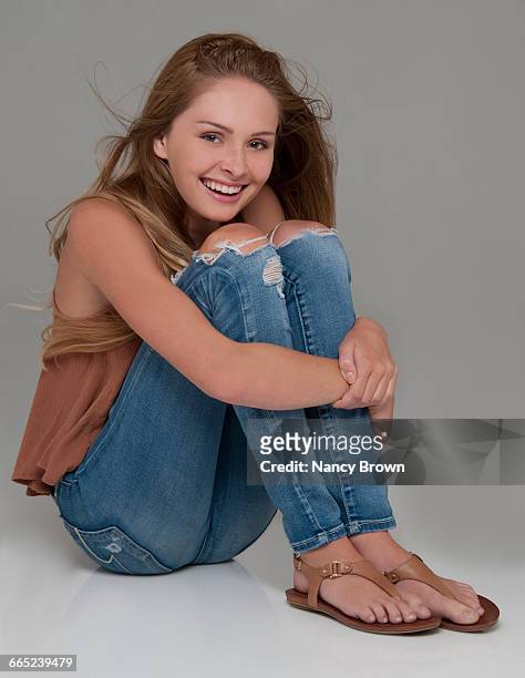 laughing teenage girl in torn jeans on grey. - une seule adolescente photos et images de collection