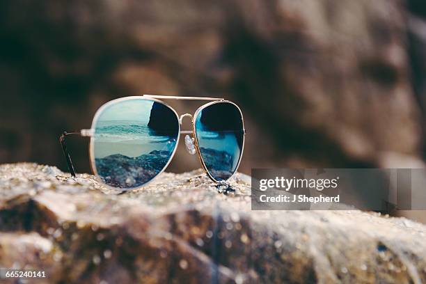 sunglasses reflecting the shoreline. - mirrored sunglasses stock-fotos und bilder