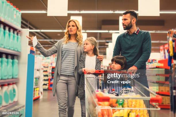 familie, einkaufen im supermarkt - frau einkaufswagen ernst stock-fotos und bilder